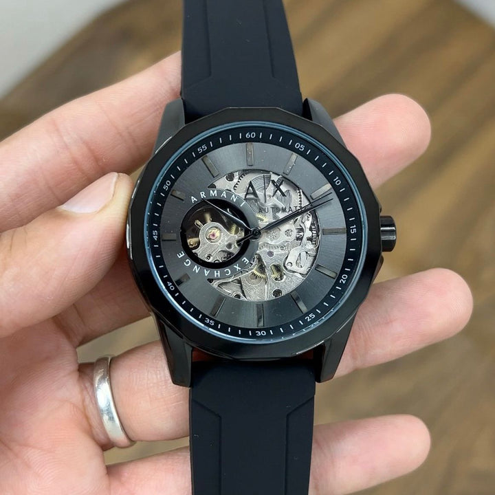 Black Armani watch held in a hand with a blurred background