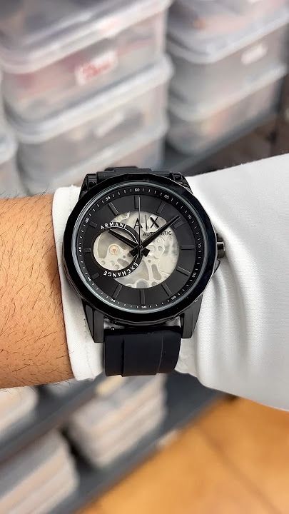 Black wristwatch on a person's wrist with a blurred background